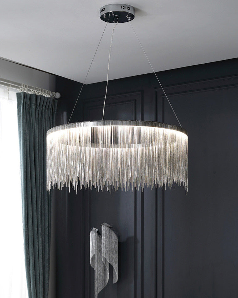 Silver chandelier glowing against dark wall panels, its reflective fringe transforming a simple ring of light into a sculptural evening centerpiece.