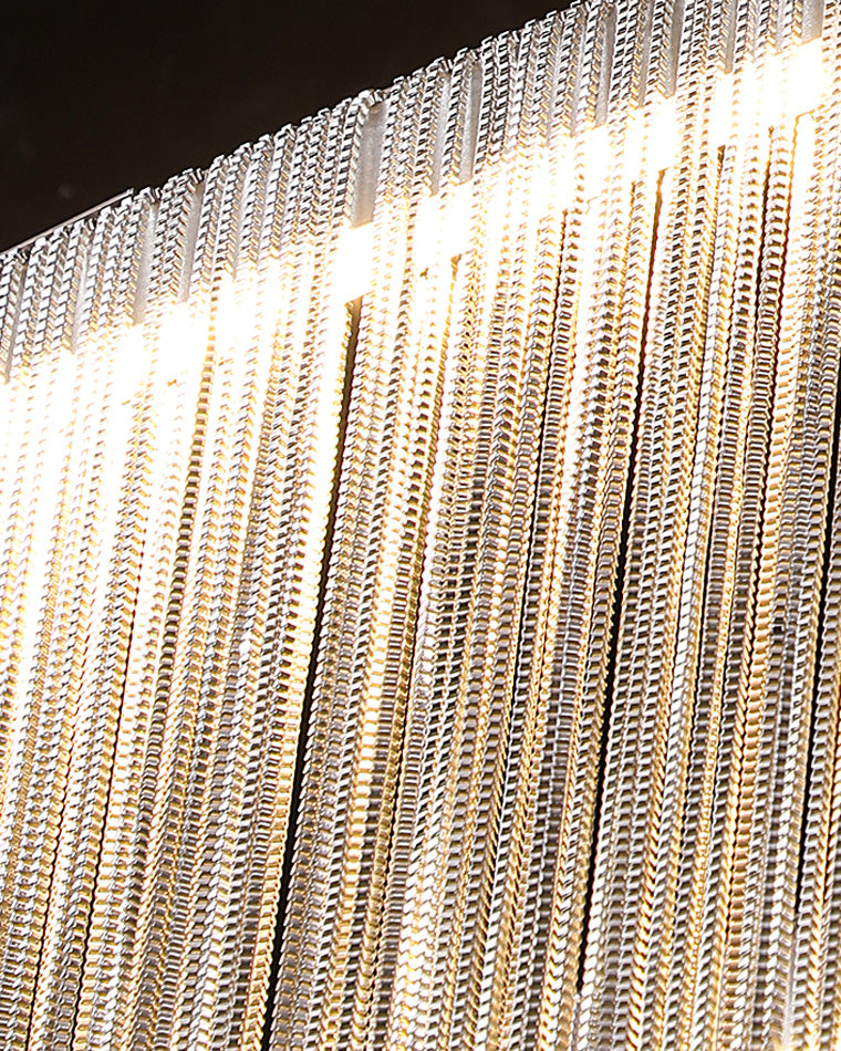 Close-up of illuminated silver chain fringe, revealing the dense texture and softly diffused sparkle behind the chandelier’s rain-like glow.