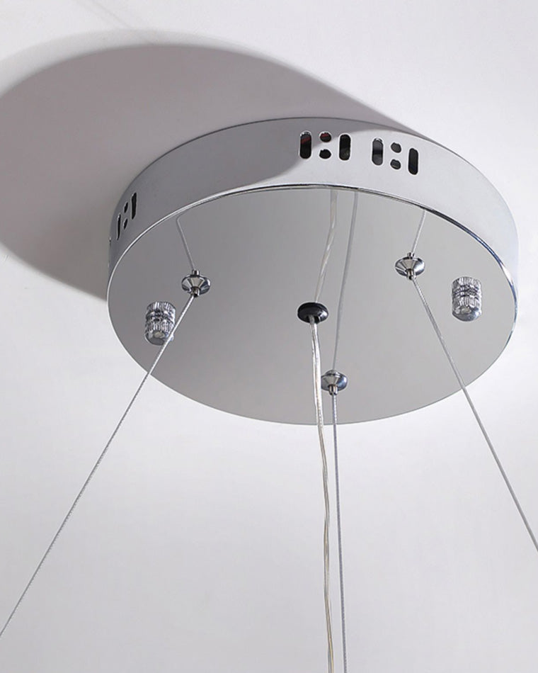 Polished silver ceiling canopy with suspension cables and discreet ventilation slots, supporting a clean installation and a visually floating chandelier profile.