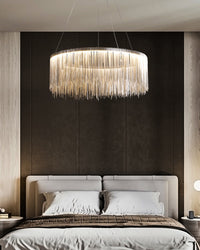 Silver round chandelier above a bed with a black upholstered wall, providing a glamorous focal point in interior design while keeping the sleeping area composed.