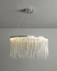 Illuminated silver waterfall chandelier displayed against a neutral background, revealing the soft halo and rippling shine created by its descending chains.