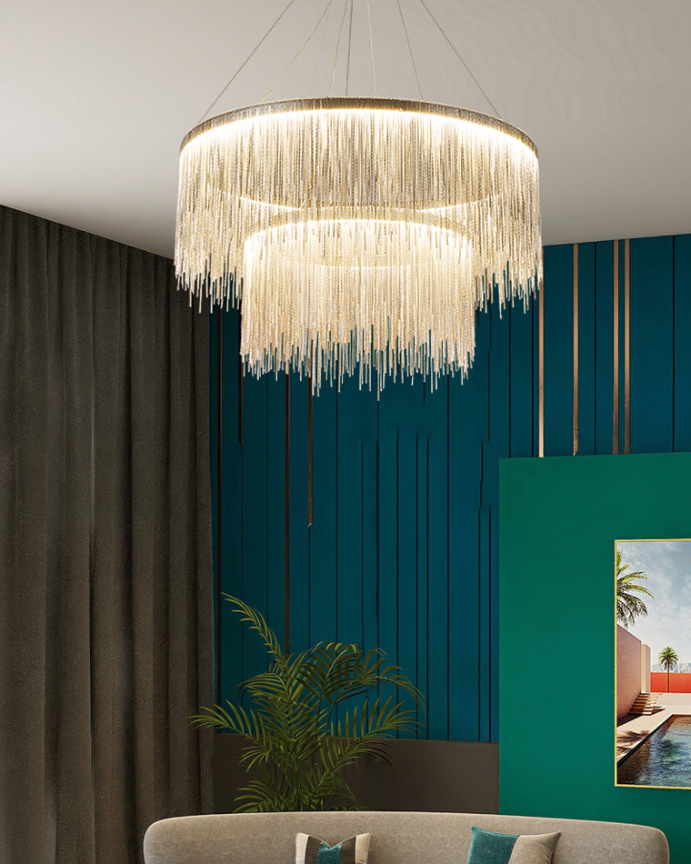 Gold chandelier glowing against a teal wall, where layered chain fringe builds depth and gives the room the decadent charm of a reimagined vintage chandelier.