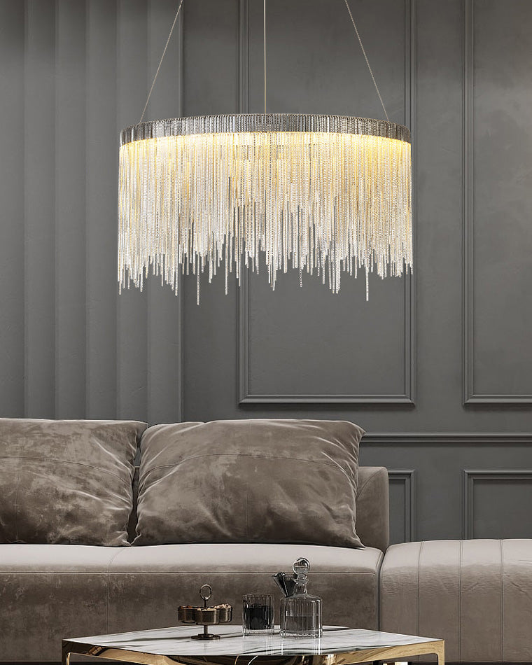 Silver chandelier above a gray sofa and dark paneled wall, balancing a strong architectural backdrop with soft, reflective movement.