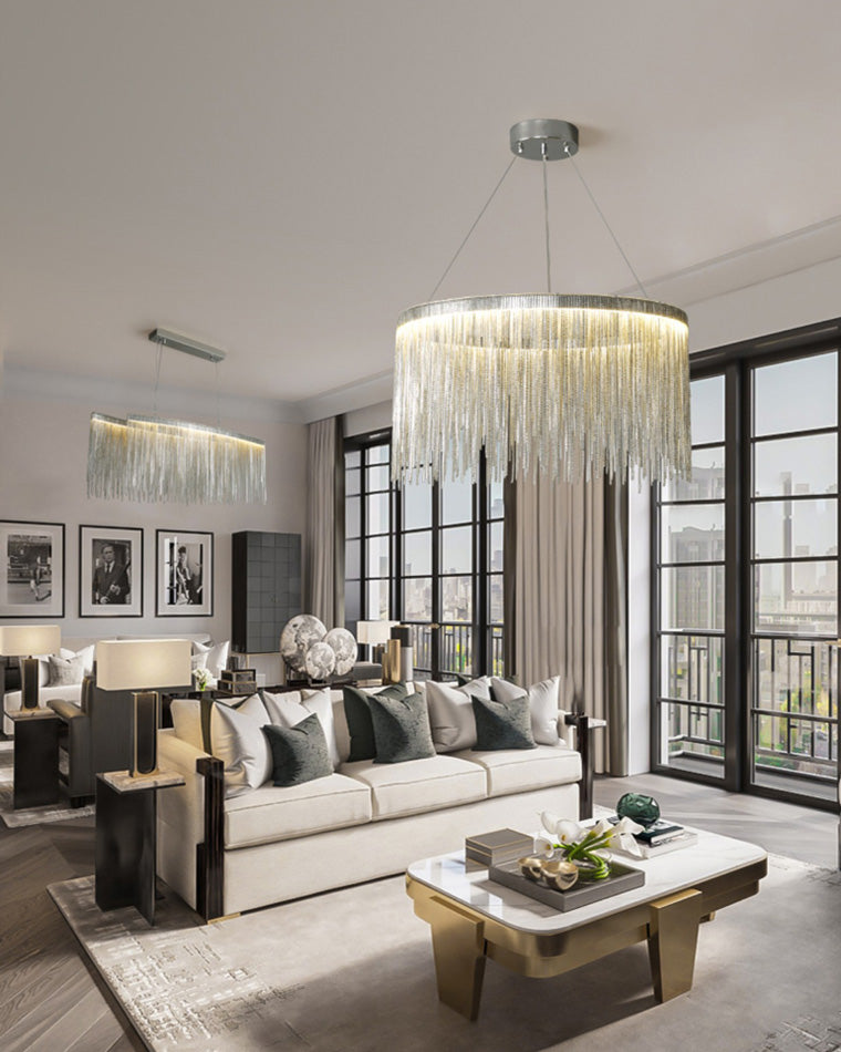 A prominent silver fringe chandelier anchors the living area while a second matching light appears in the background, creating visual rhythm across the open-plan interior.