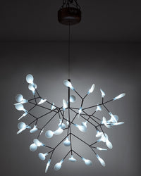 Illuminated black Firefly organic chandelier against a dark background, where glowing acrylic leaves resemble a swarm suspended in the night.