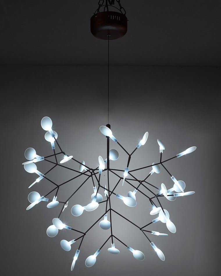 Illuminated black Firefly organic chandelier against a dark background, where glowing acrylic leaves resemble a swarm suspended in the night.