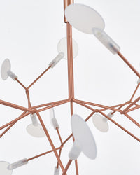 Close-up of translucent acrylic leaves and rose-gold joints, revealing how refined materials soften each firefly-like point of light.