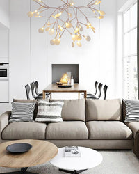 Rose-gold Heracleum organic chandelier floating above a neutral sofa, bringing firefly sparkle and sculptural depth to the calm interior.