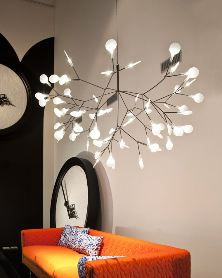 Rose-gold Firefly tree branch chandelier above an orange bed, casting a calm constellation of light for a warm and artistic bedroom.