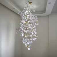 Ceramic ginkgo foyer chandelier with a round gold-toned canopy and slim suspension wires, shown illuminated in a tall interior.
