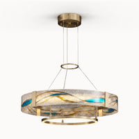 Enamel round brass chandelier in gold with textured glass, blue enamel wave inlays, slim suspension cables, and a glowing lower LED ring on a white background.
