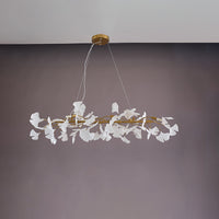 Gold 39-inch ginkgo leaf linear chandelier shown unlit with its ceramic leaves and branch frame.