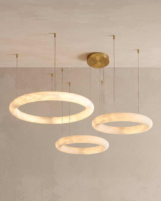 WOMO WM2873 three glowing alabaster rings of different sizes suspended at staggered heights from fine cables.