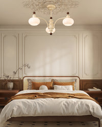 Three-light beige glass globe chandelier over a bed in a warm classic bedroom