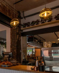 Warm glass globe pendant lights illuminating a wood-accented restaurant or café interior.