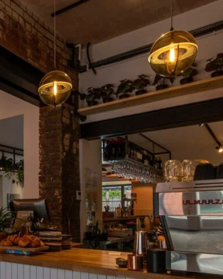 Warm glass globe pendant lights illuminating a wood-accented restaurant or café interior.