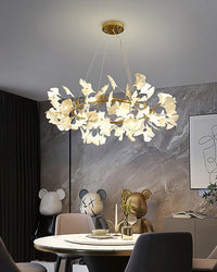 Ceramic ginkgo leaf chandelier over a round dining table with sculptural wall art.