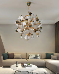 A modern living room with a beige sofa and decorative cushions; a white and gold ginkgo leaf chandelier hangs overhead, shown in a close-up.