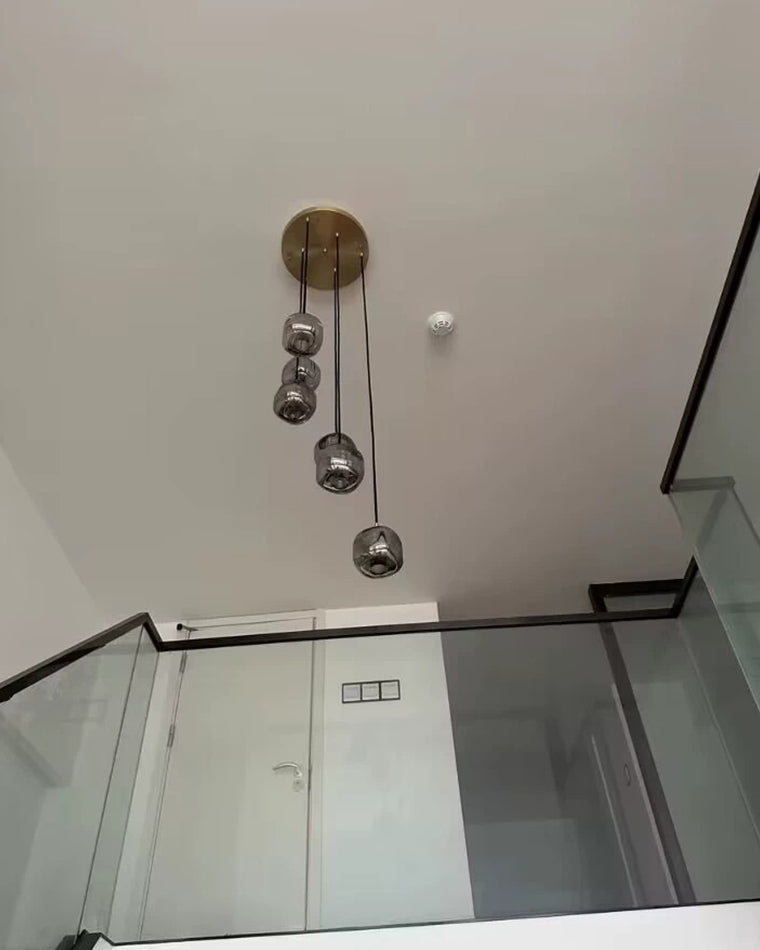Floor-level view of a compact smoked-glass pendant chandelier beneath a high ceiling, highlighting rounded shade forms and vertical drop.