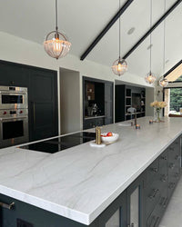 Clear-and-white glass pendant lights for a kitchen island in a modern dark-cabinet kitchen.