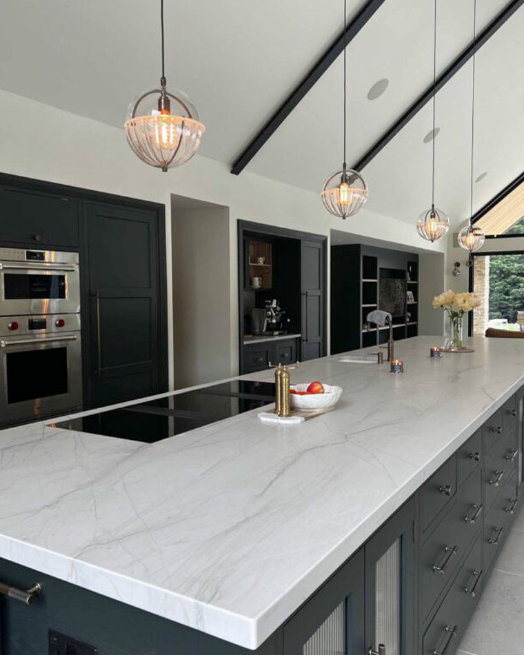 Clear-and-white glass pendant lights for a kitchen island in a modern dark-cabinet kitchen.