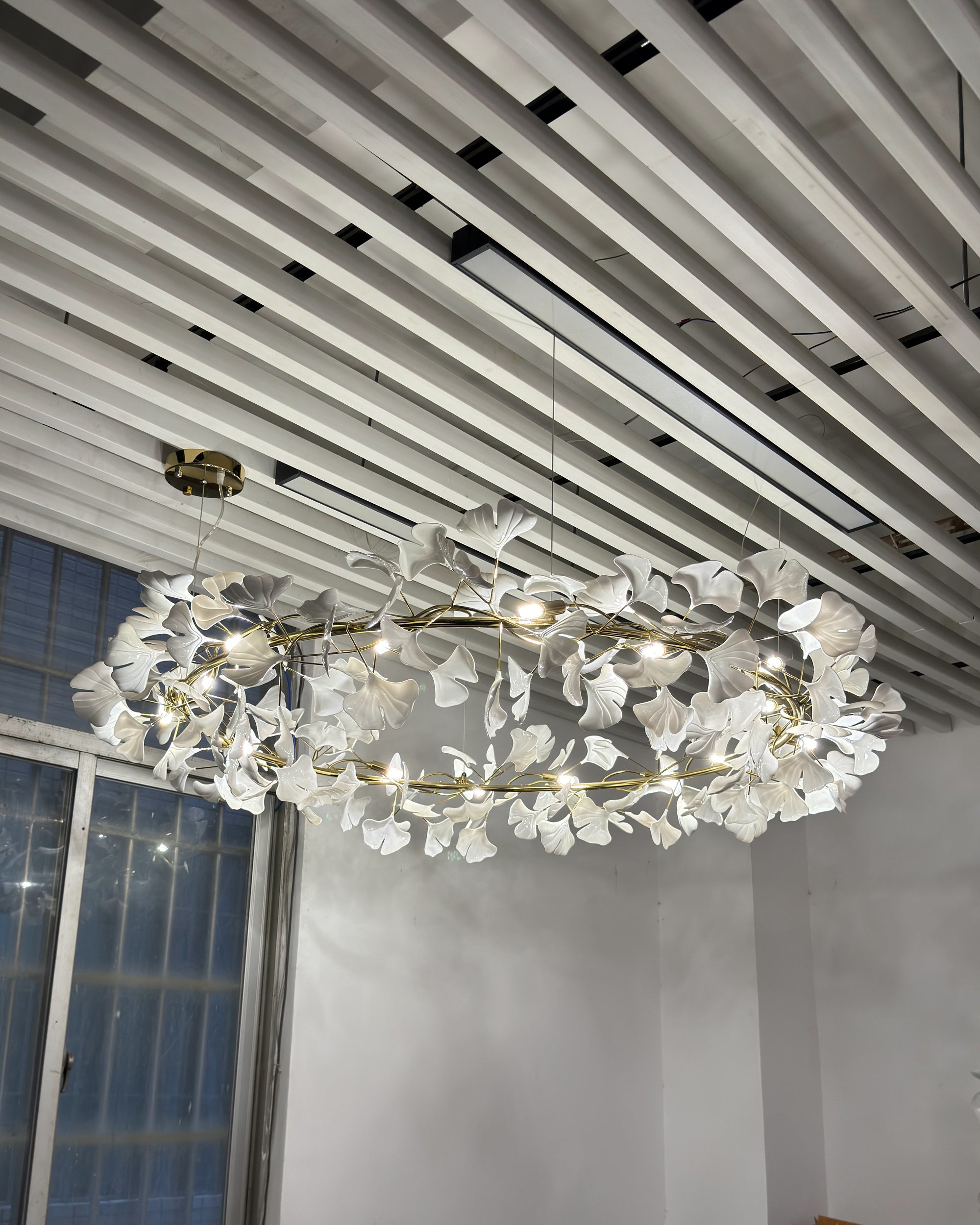 Illuminated WM2414 round chandelier viewed from below near a window.