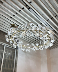 Round ceramic leaf chandelier viewed from below beneath a slatted ceiling.