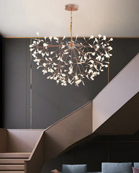 Rose-gold modern organic chandelier illuminating a dramatic stairway, softening strong architectural lines with a floating botanical glow.
