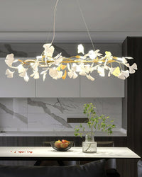 Gold ginkgo branch chandelier over a marble kitchen island, showing its long horizontal profile.