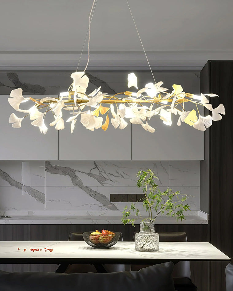 Gold ginkgo branch chandelier over a marble kitchen island, showing its long horizontal profile.