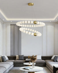 Layered pearl rings bring the refined presence of a visual comfort chandelier above a spacious gray living room, adding light, movement, and jewelry-like elegance.