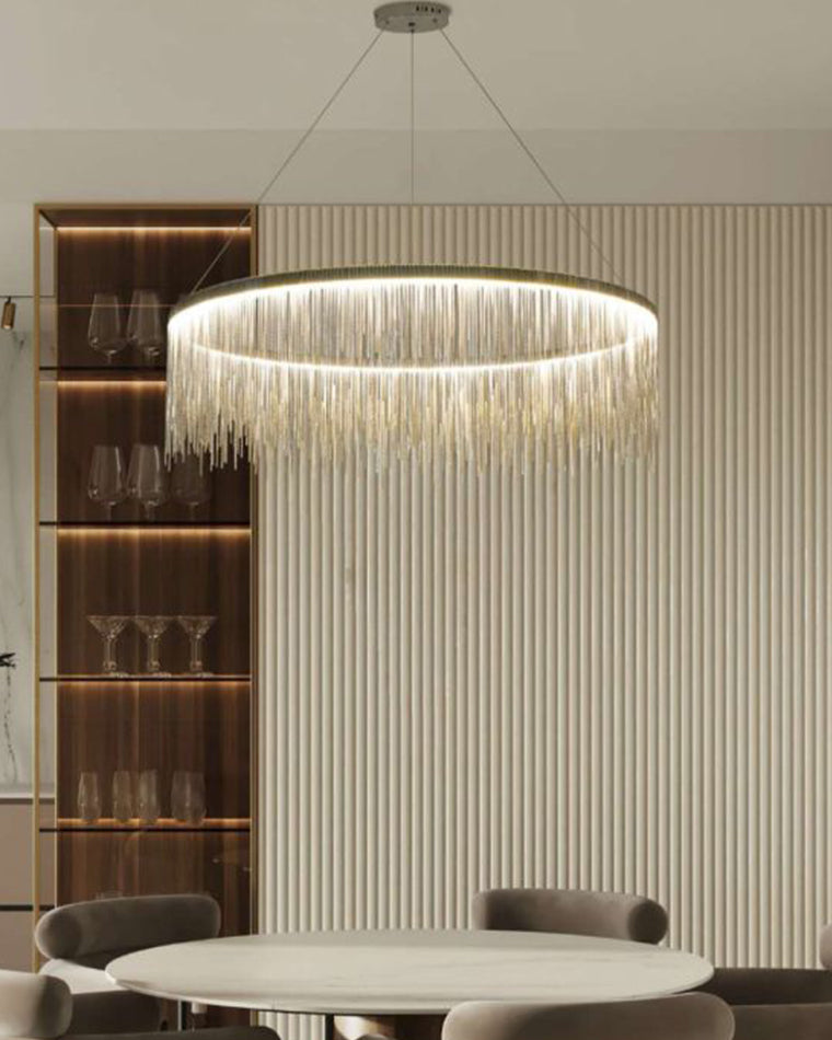 Silver fringe chandelier casting focused yet flattering light over a round dining table, balanced by ribbed walls and softly illuminated display shelves.