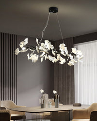 Black ginkgo leaf linear chandelier above a modern dining table with neutral decor.