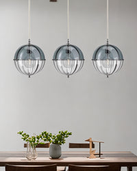 Blue globe pendant lights arranged above a minimalist dining table with soft wall lighting.