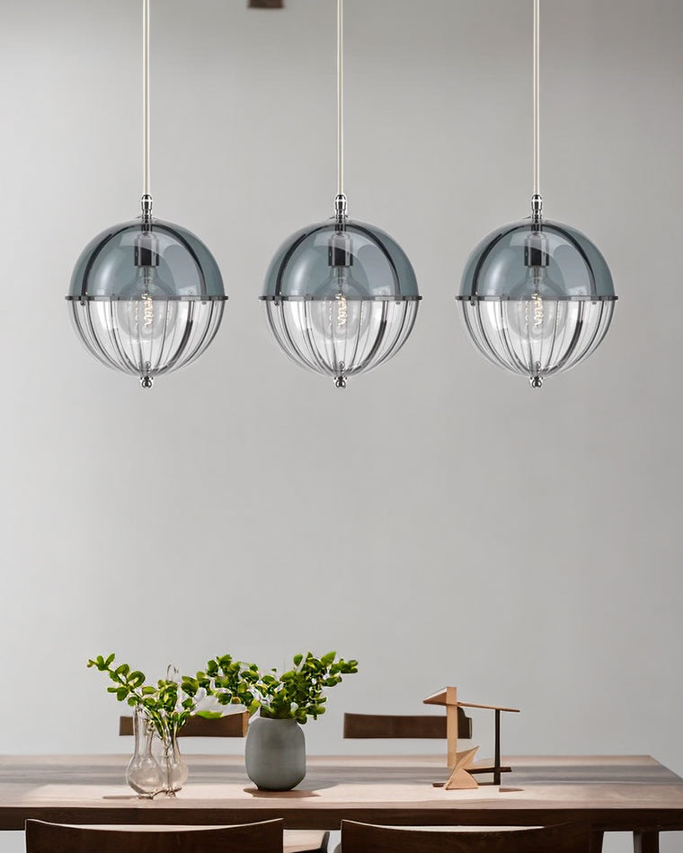 Blue globe pendant lights arranged above a minimalist dining table with soft wall lighting.