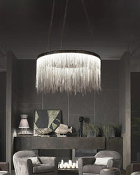 Large silver chandelier illuminating a dark gray lounge, where cascading chains break up the heavy palette with fluid highlights and atmospheric light.