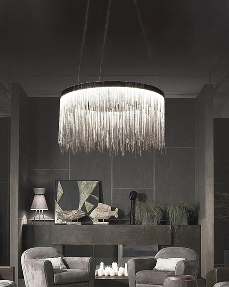 Large silver chandelier illuminating a dark gray lounge, where cascading chains break up the heavy palette with fluid highlights and atmospheric light.
