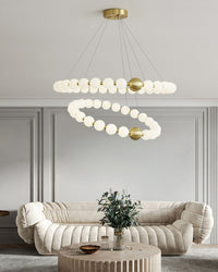 Quiet luxury takes shape in two floating pearl rings above a curved cream sofa, where luminous white globes and restrained gold accents enrich the room.
