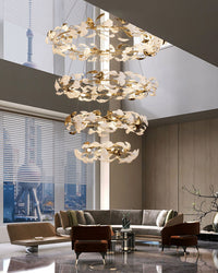 Illuminated high ceiling chandelier cascading through a double-height living room with city views.