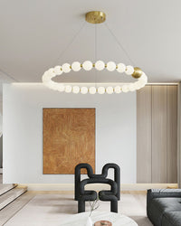 Single-ring pearl chandelier casts a continuous halo above the lounge, while its statement gold sphere turns practical lighting into a polished centerpiece.