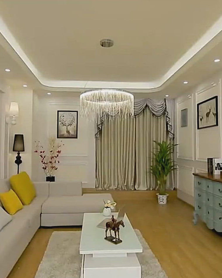 Silver round chandelier suspended in a bright white living room, adding shimmer and definition while preserving the room’s calm, spacious character.