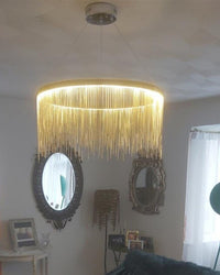 Gold chain-fringe light enriching a mirror-lined living room with the decorative glamour of a vintage chandelier, softened for contemporary interiors.