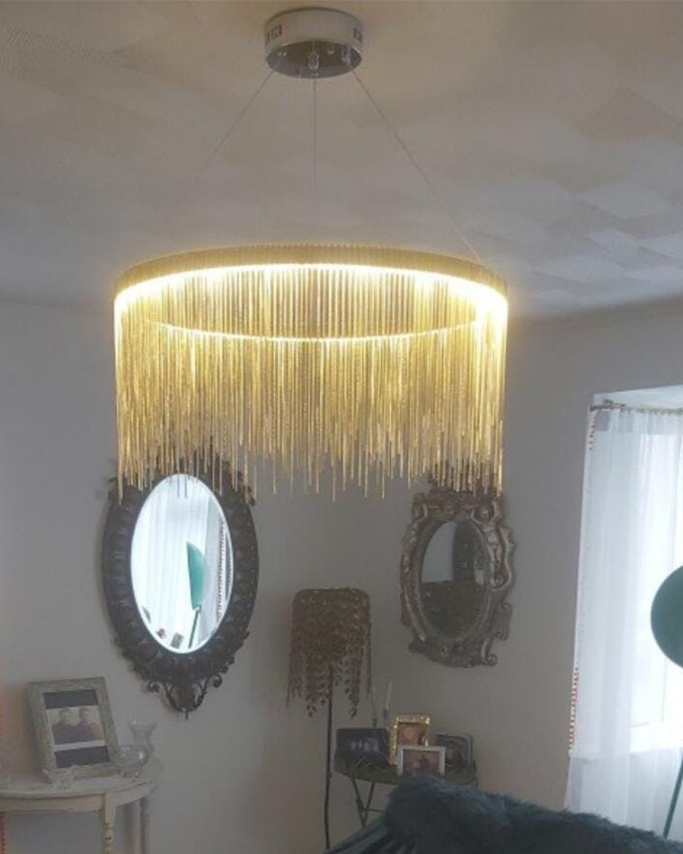 Gold chain-fringe light enriching a mirror-lined living room with the decorative glamour of a vintage chandelier, softened for contemporary interiors.