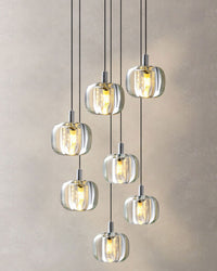Seven clear glass pendants suspended at varied heights on a compact cluster pendant chandelier, ideal for a calm, modern entry or dining corner.