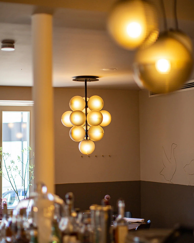 Glowing grape chandelier suspended above a warm modern dining space.