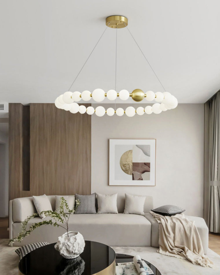 A luminous pearl ring brightens the wood-toned living room, balancing a clean circular profile with restrained gold detailing and an airy suspended form.