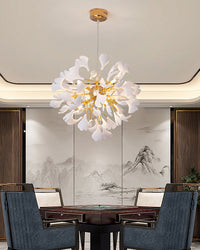 A cozy game/dining room with a square wooden table and four chairs; a white and gold ginkgo leaf chandelier hangs above the center of the table.