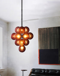 Illuminated grape chandelier hanging against a bright minimalist living room wall.