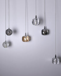 Amber, smoked, and clear pendants arranged asymmetrically on the waterfall glass chandelier, emphasizing the mixed-glass palette and relaxed vertical spacing.