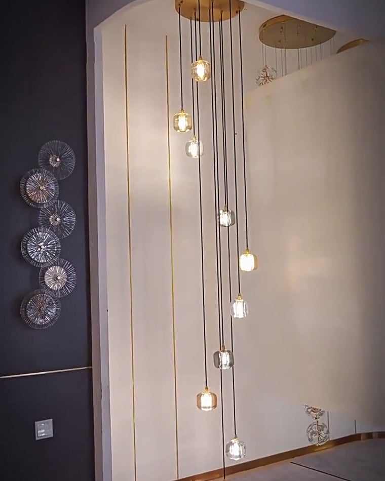 Long-drop foyer chandelier with slender glowing pendants, designed to fill vertical space beside statement wall art in an entryway.